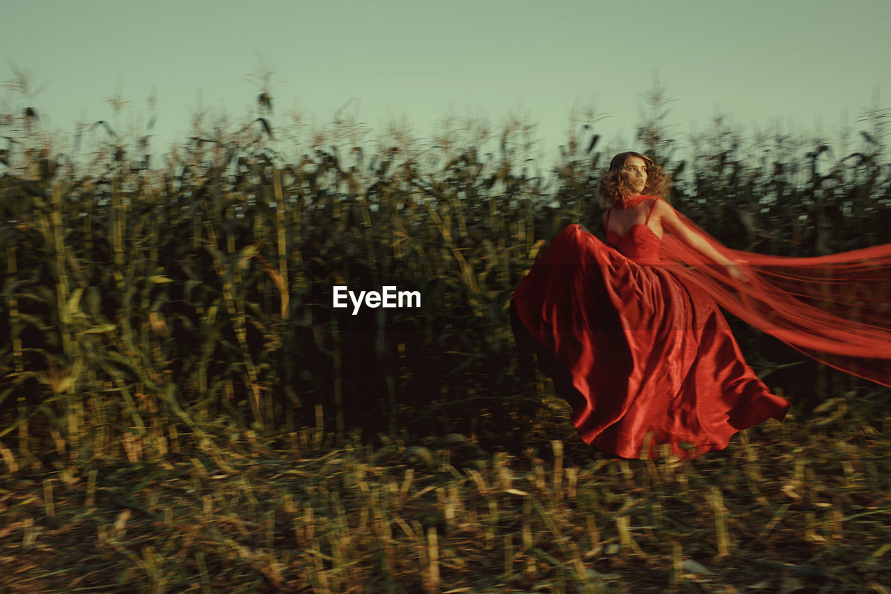 Woman wearing red dress standing amidst plants