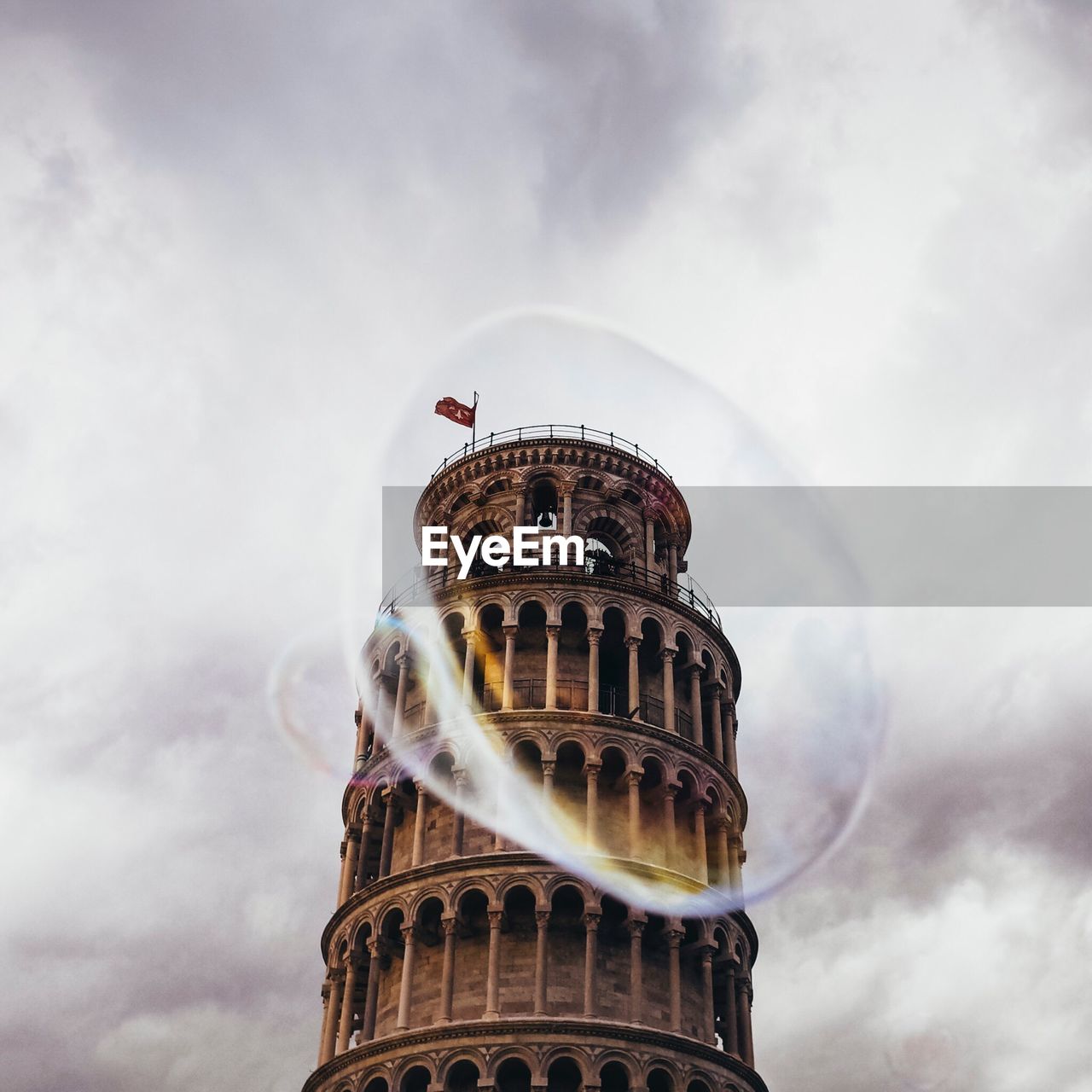 Leaning tower of pisa seen through bubbles against cloudy sky