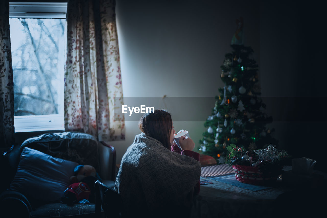 Woman drinking coffee at home during christmas