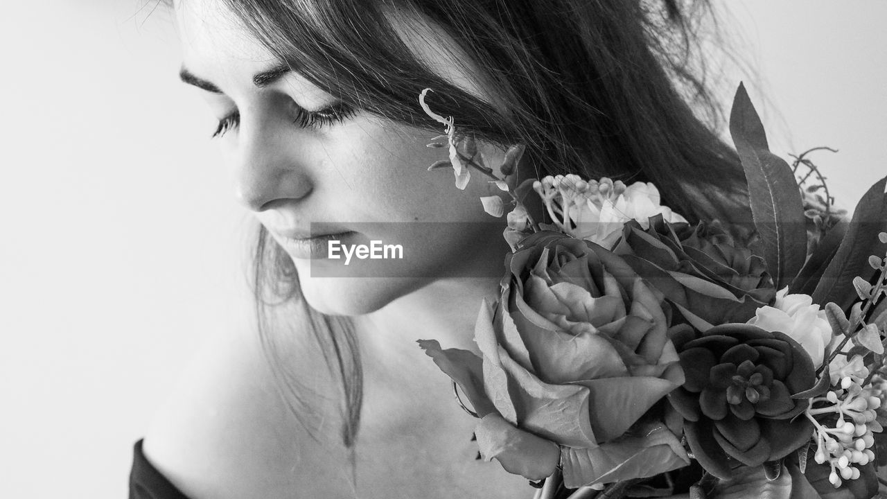 CLOSE-UP PORTRAIT OF BEAUTIFUL WOMAN AGAINST RED AND WHITE ROSE