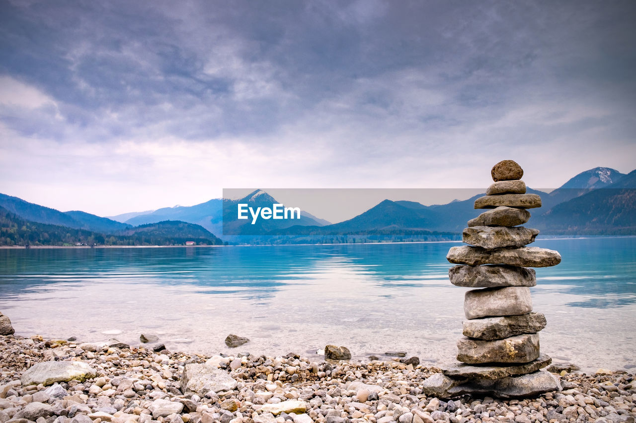 Pile stones on beach. rock heap of gray dolomite pebbles close to alpine lake, mountains silhouettes