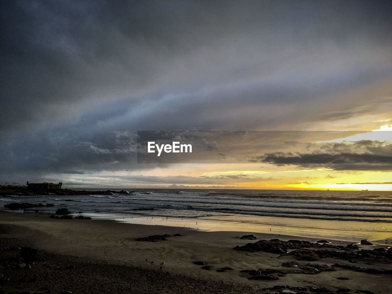 VIEW OF BEACH AGAINST DRAMATIC SKY