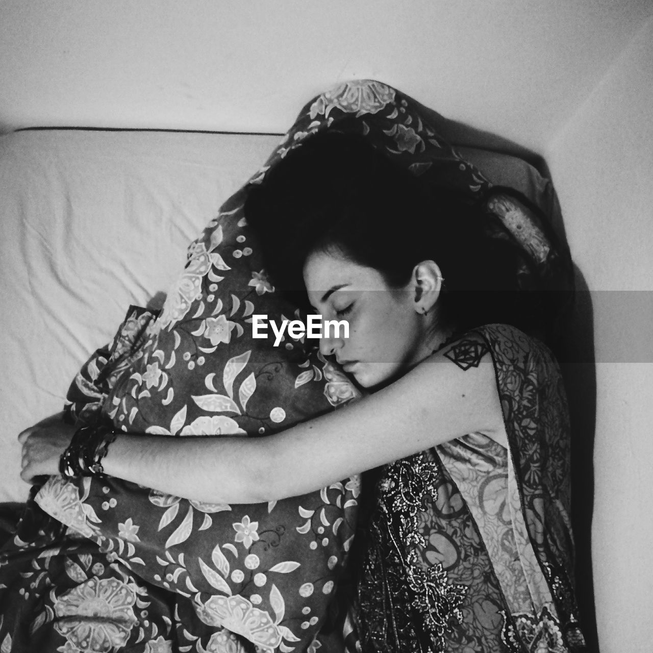 Side view of young woman sleeping with pillow on bed at home