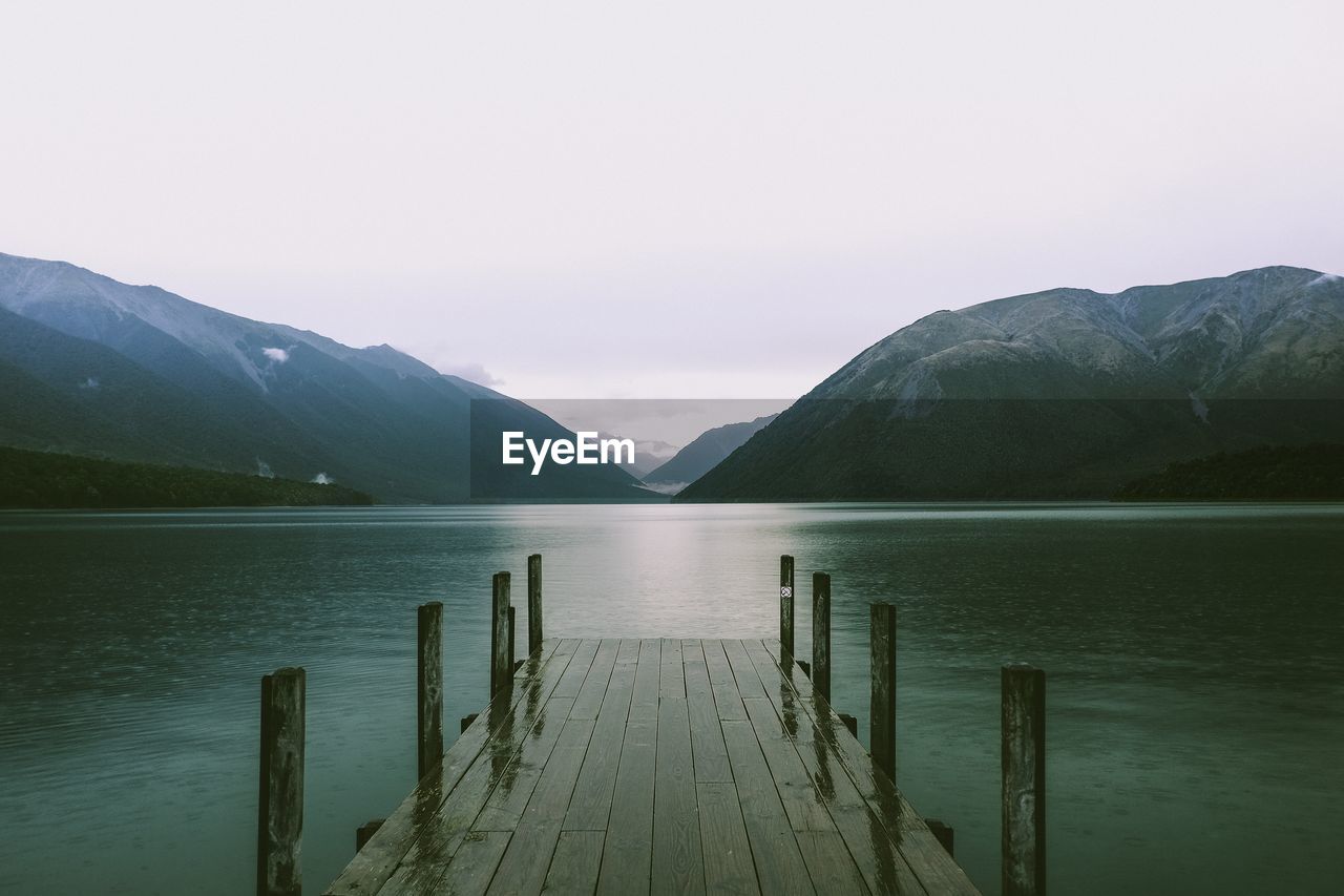 Wooden pier over lake against mountains