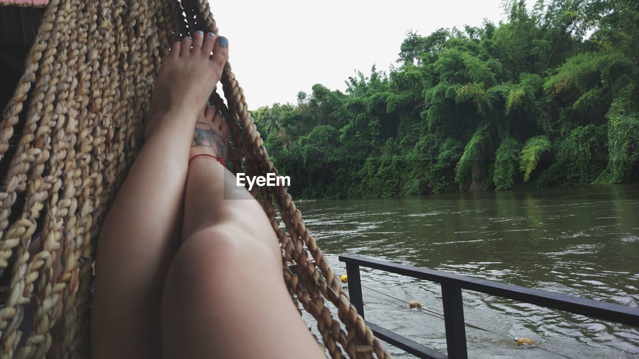 Low section of woman in hammock by lake