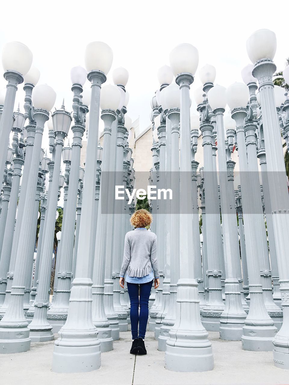 Rear view of woman standing amidst lamp posts