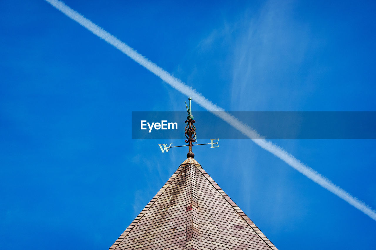 Low angle view of building against blue sky with contrail
