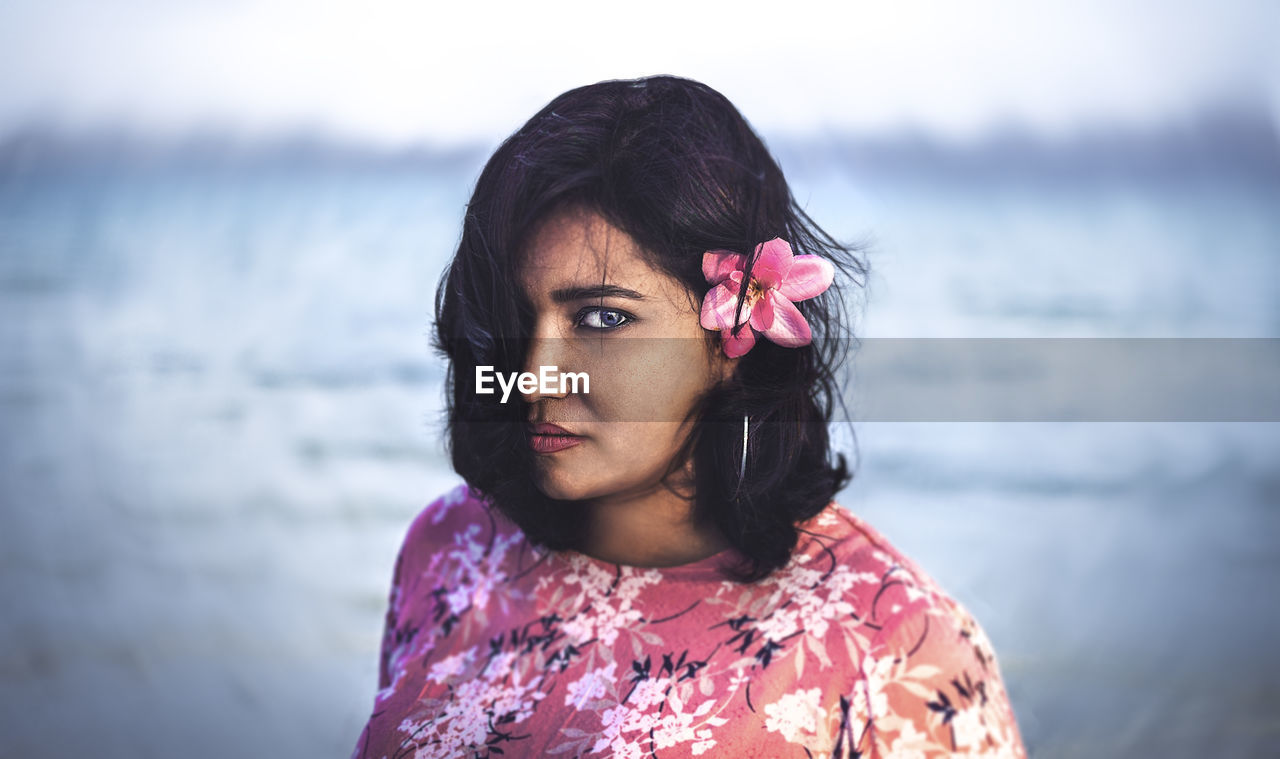 Portrait of young woman standing against sea