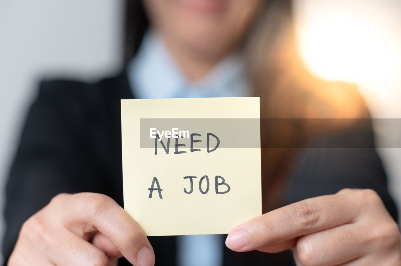 Women holding need a job text on paper note pad. 