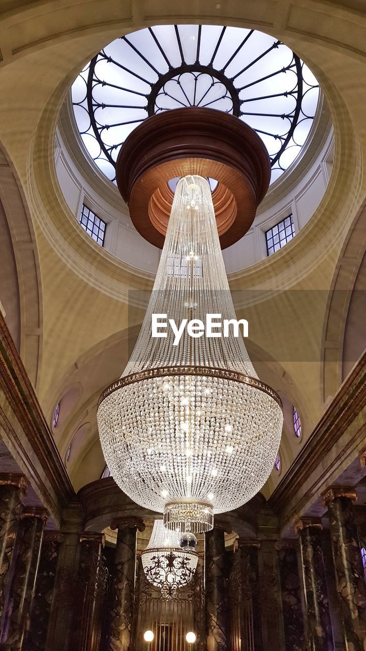 LOW ANGLE VIEW OF ILLUMINATED CHANDELIER HANGING IN BUILDING