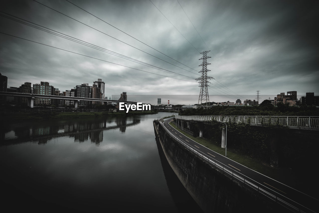 Bridge over river by buildings against sky in city