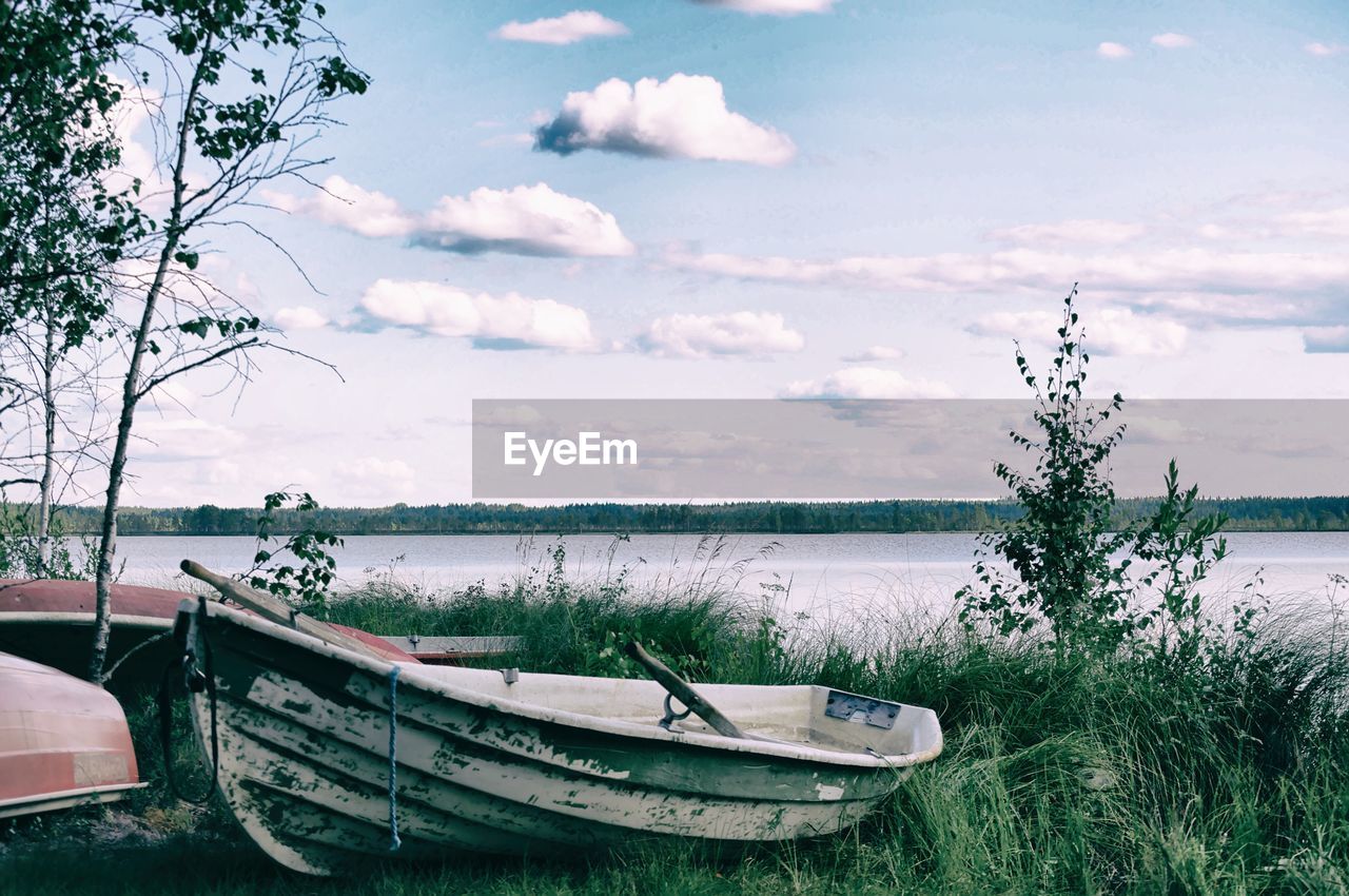 FISHING BOAT MOORED IN LAKE AGAINST SKY