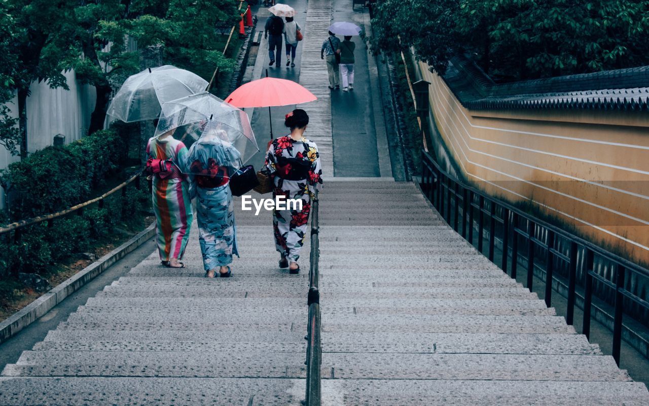 High angle view of women in traditional cloth with umbrella walking on steps
