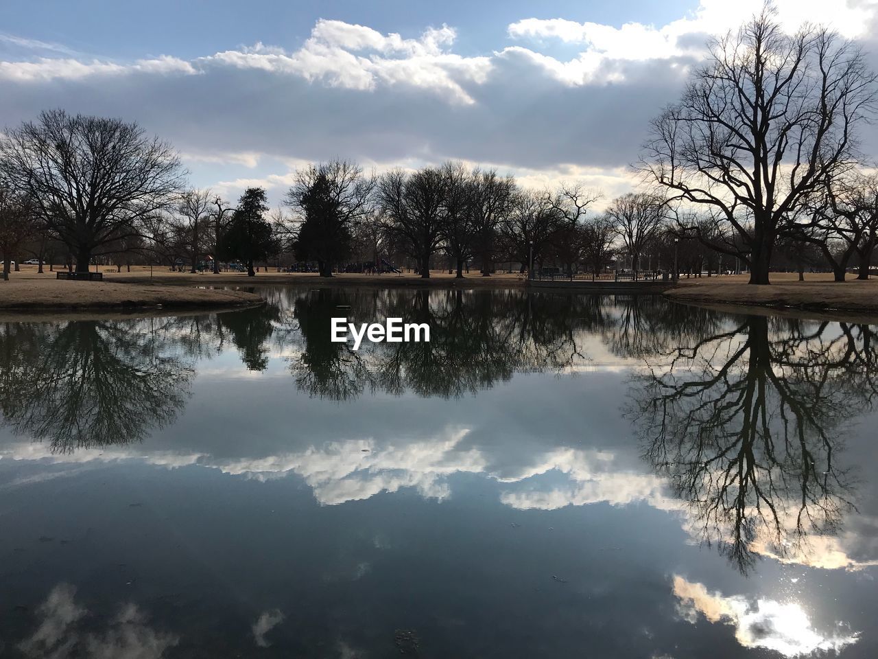 REFLECTION OF TREES ON LAKE AGAINST SKY