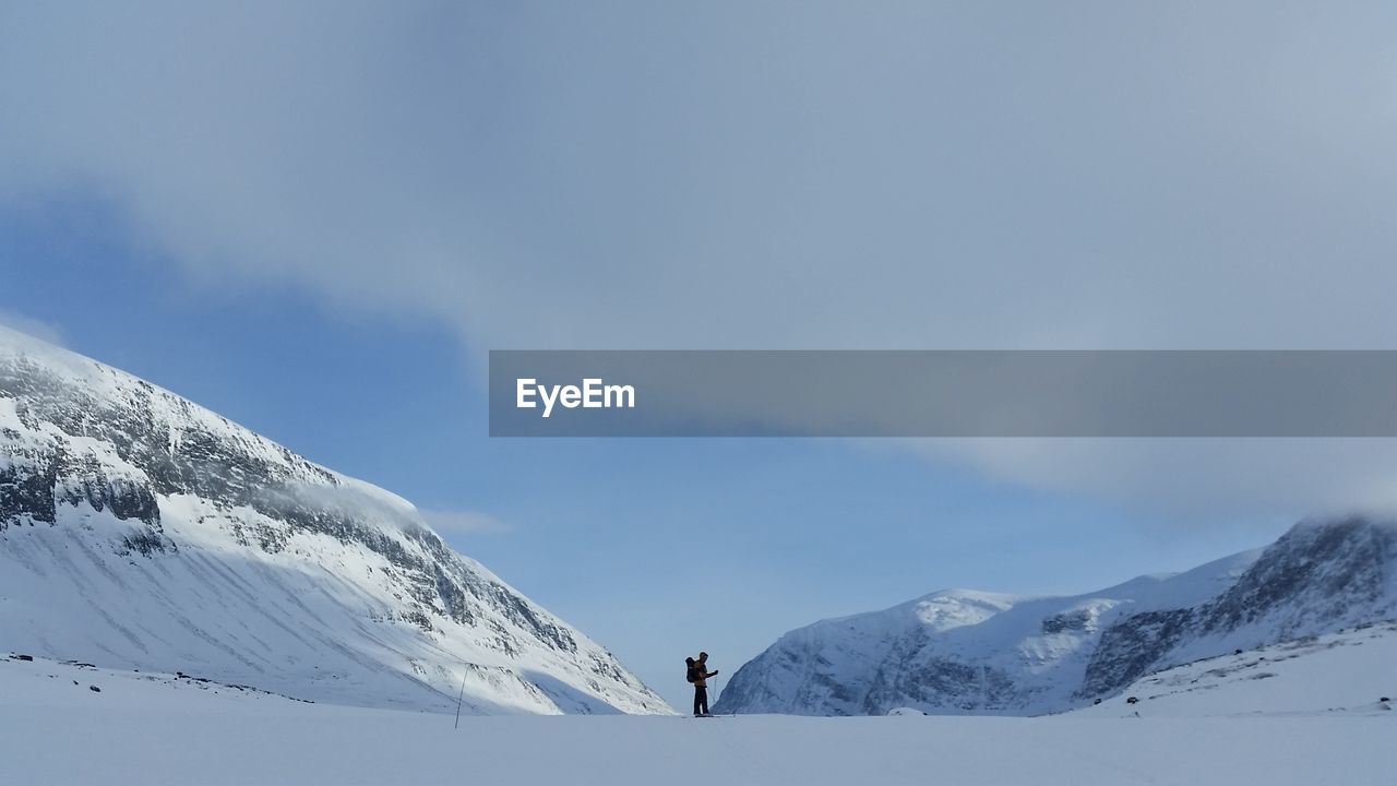 Scenic view of hiker in snowcapped mountains of kungsleden against sky