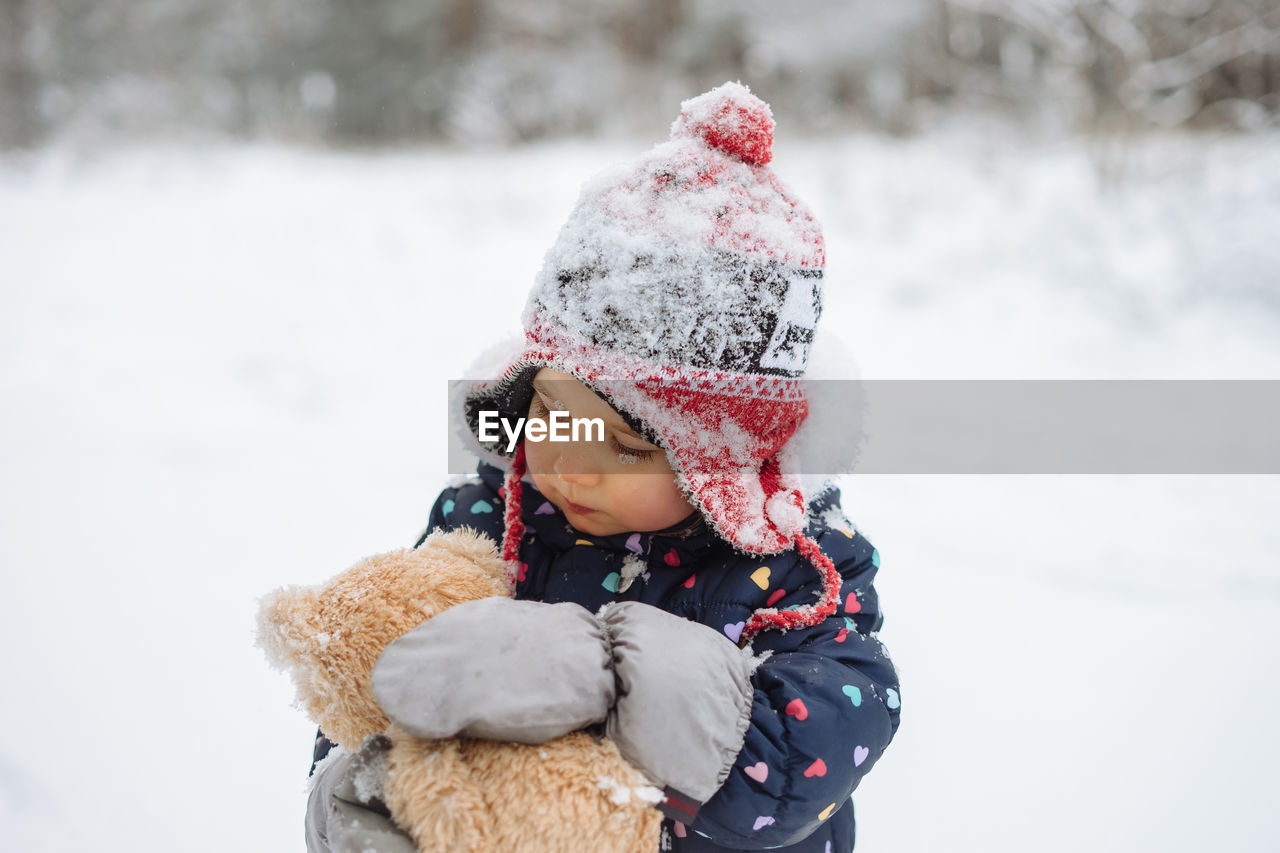 Portrait of cute little girl having fun playing outdoor during snowfall. 