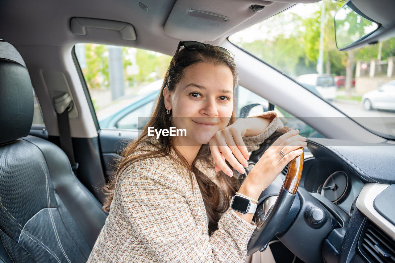 portrait of young woman using mobile phone while sitting in car