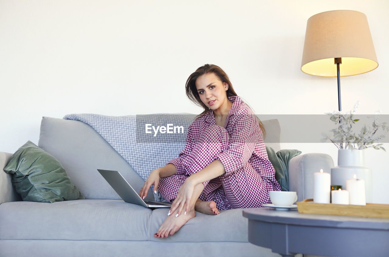PORTRAIT OF WOMAN SITTING ON SOFA