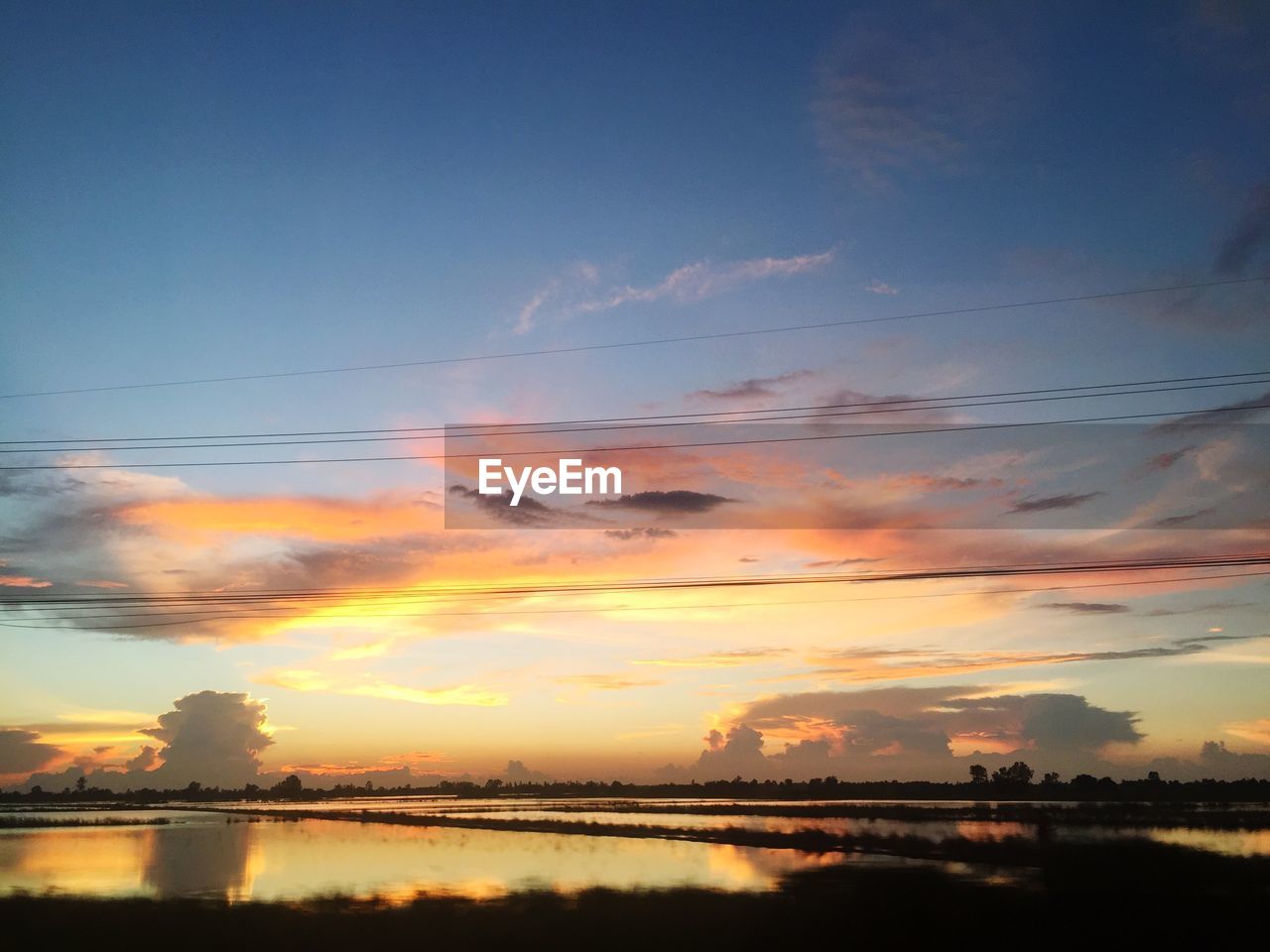 SCENIC VIEW OF SILHOUETTE SHORE AGAINST SKY AT SUNSET