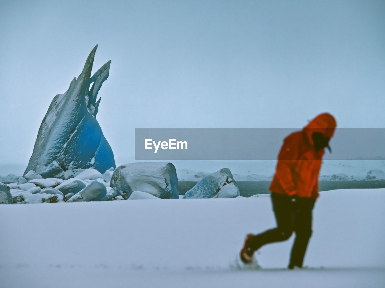 Full length of man walking in snow covered field against sky