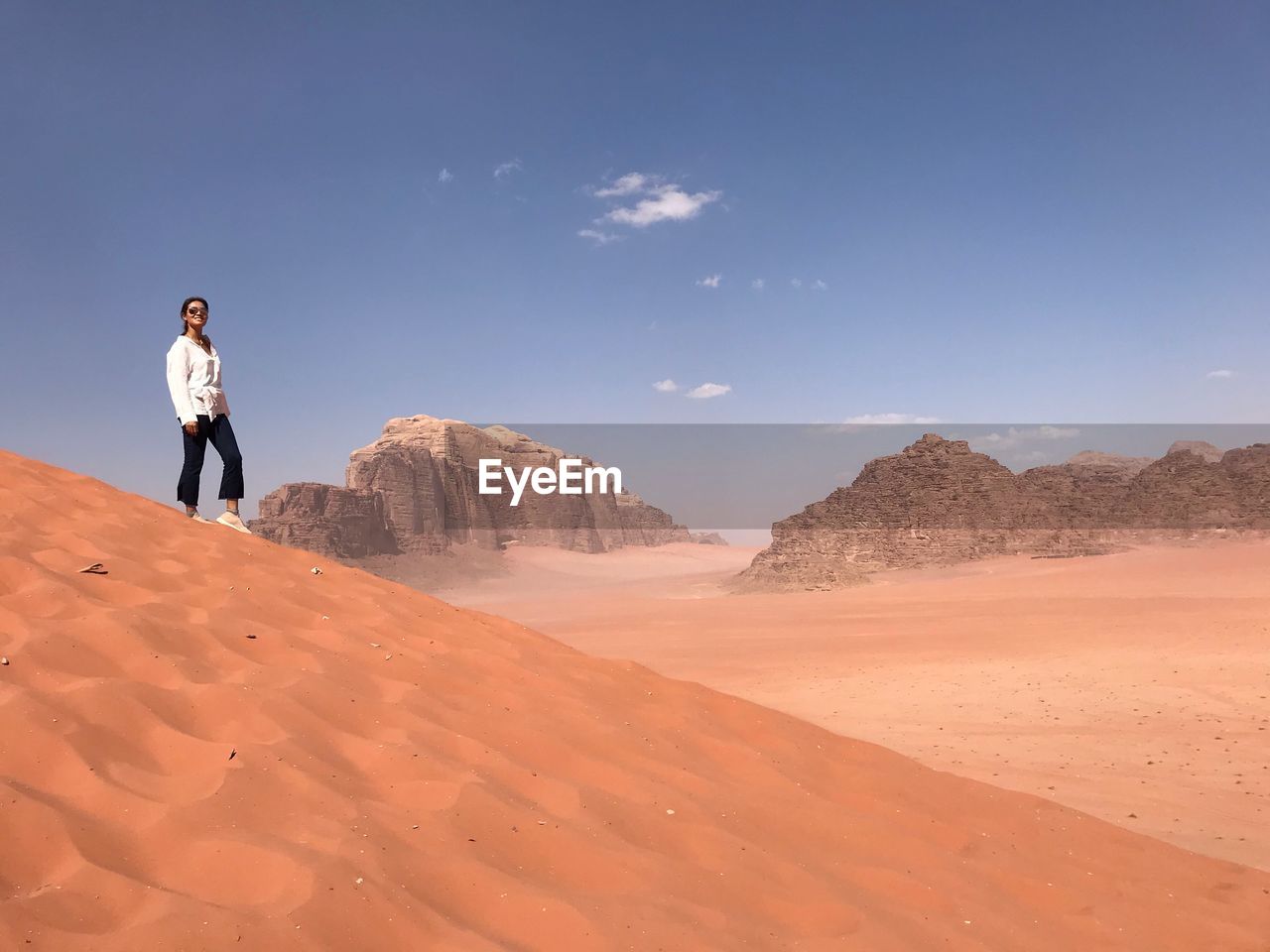 Woman standing at desert against sky