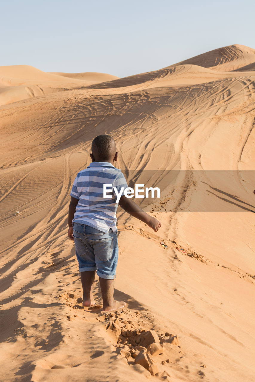 Rear view of boy on sand dune