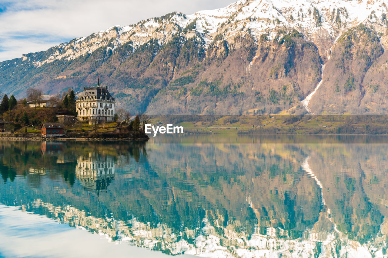 Reflection of building in lake against snowcapped mountains