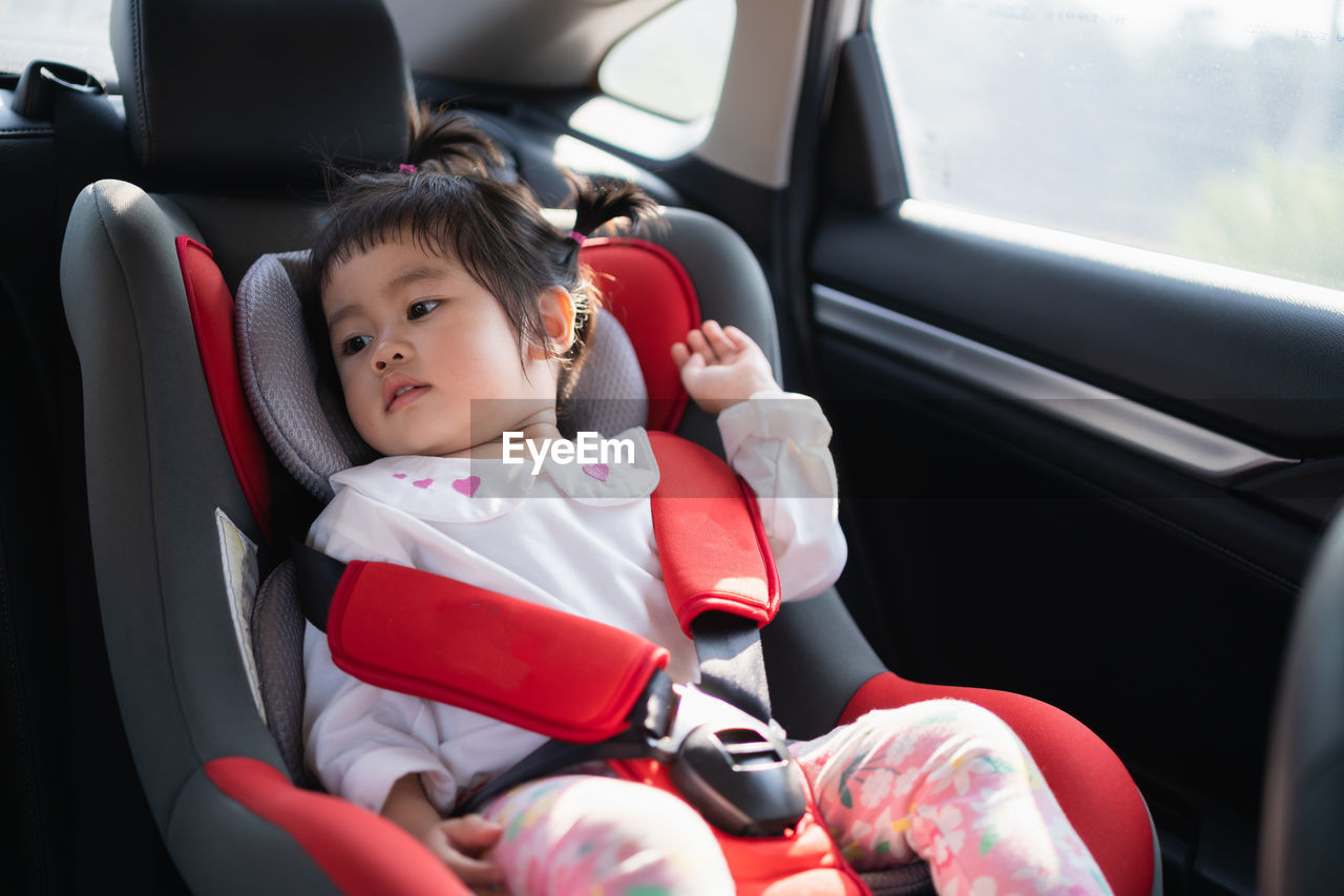 Close-up of cute girl sitting in car