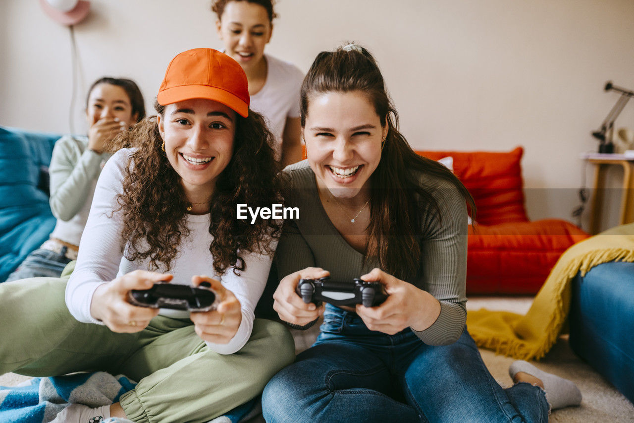 Young female friends enjoying video game at home