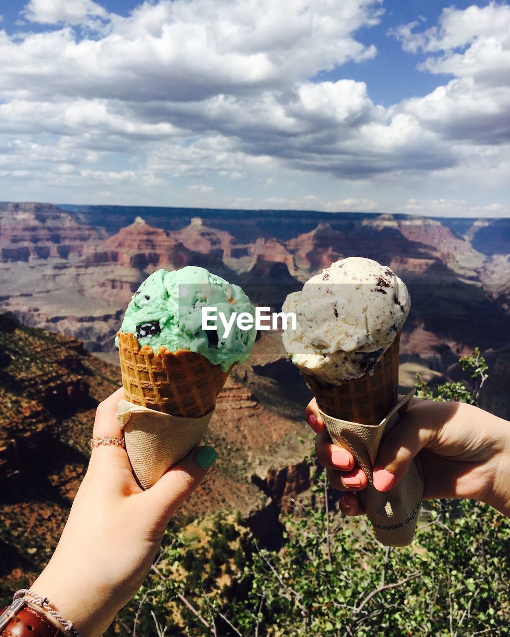 MAN HOLDING ICE CREAM CONE AGAINST SKY