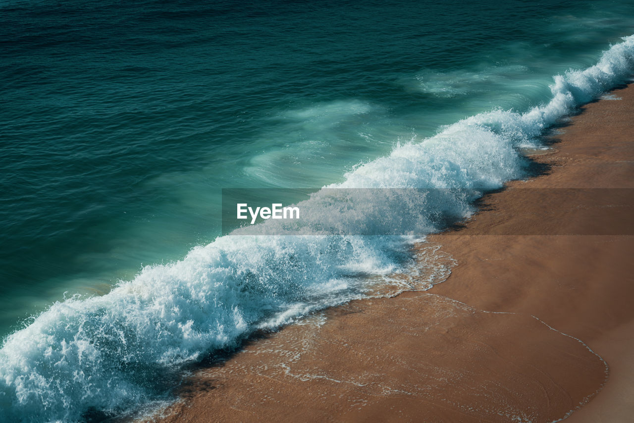 High angle view of waves rushing towards shore