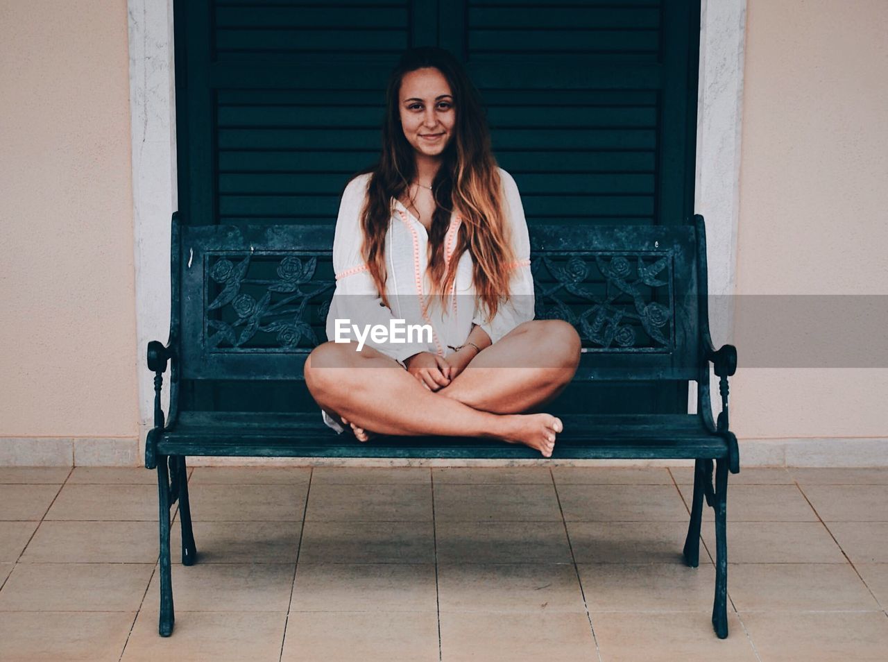 Portrait of woman sitting on bench against door