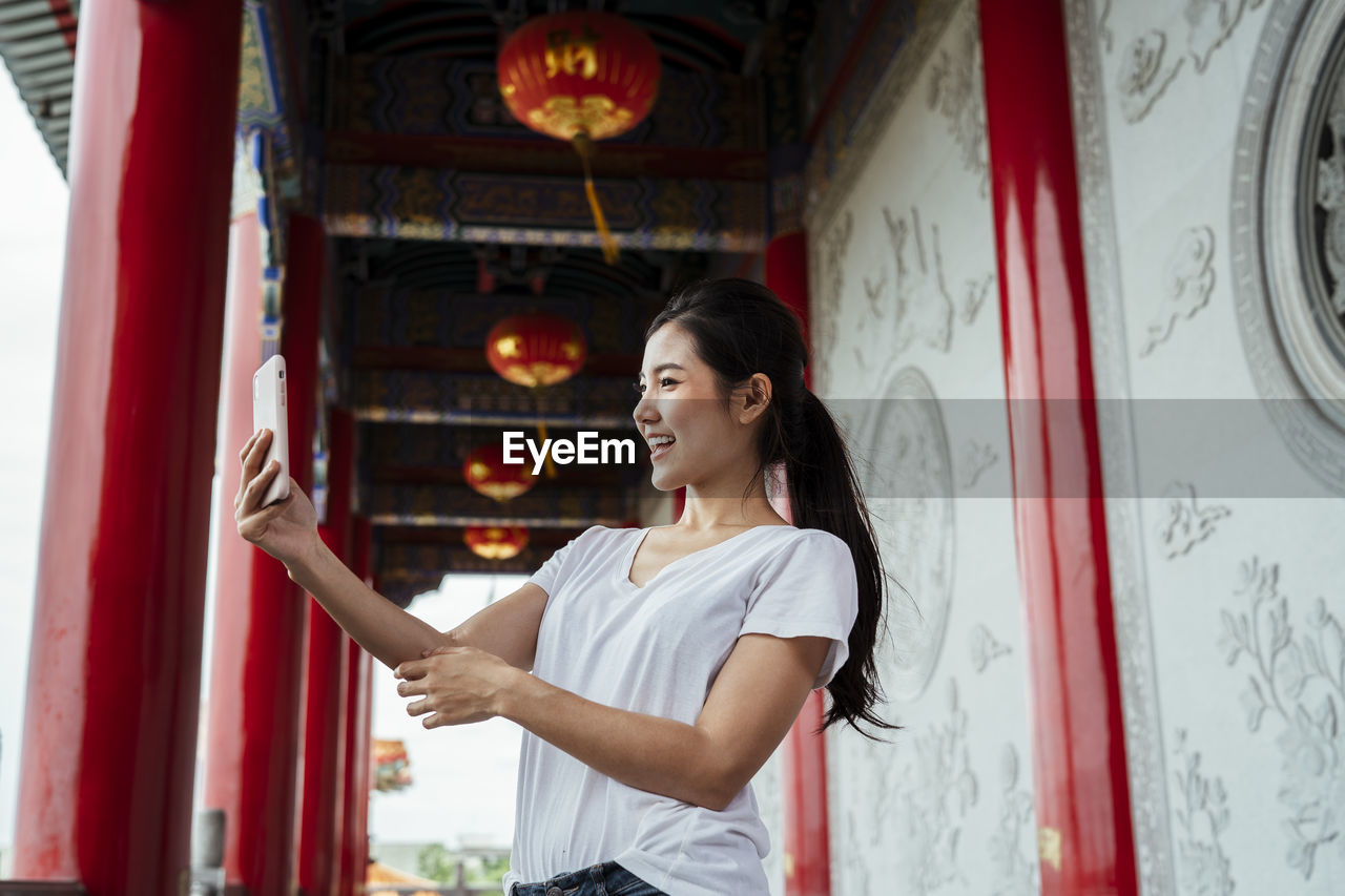 Woman using smart phone while standing in corridor