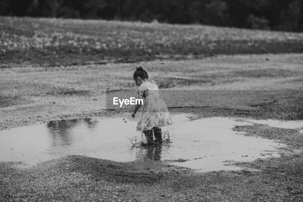 Full length of girl splashing water from puddle at beach