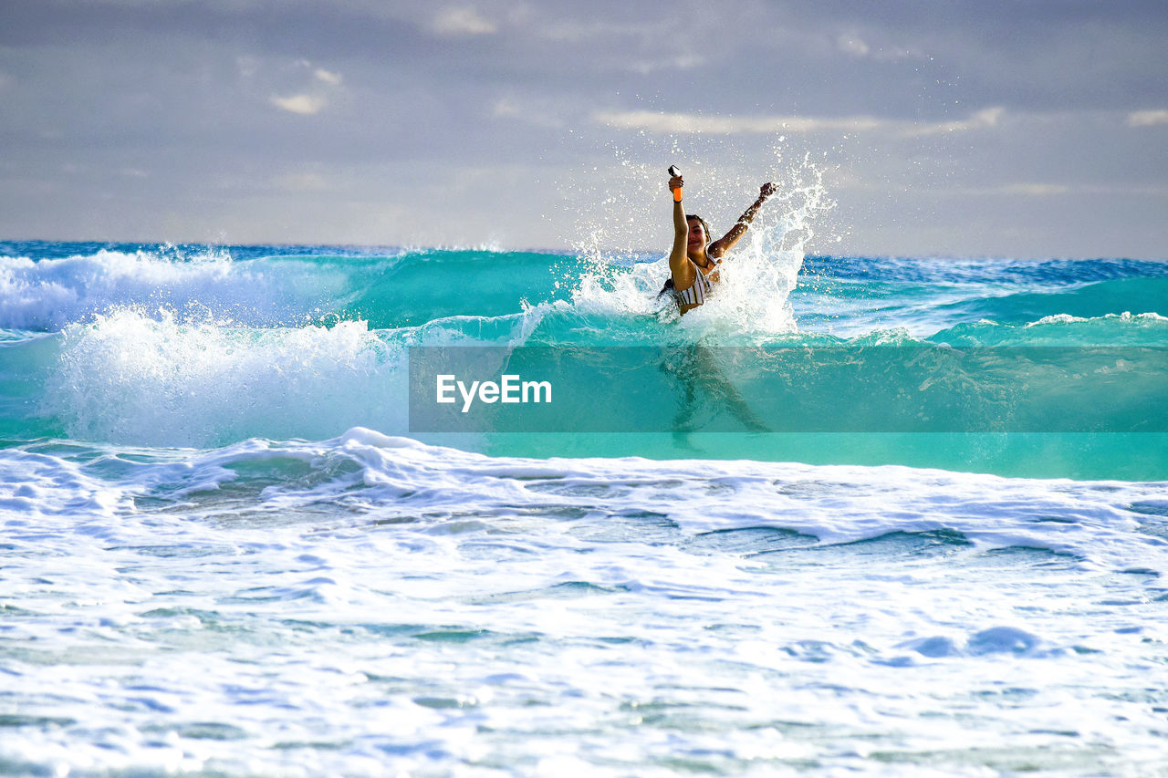 rear view of man surfing on sea against sky