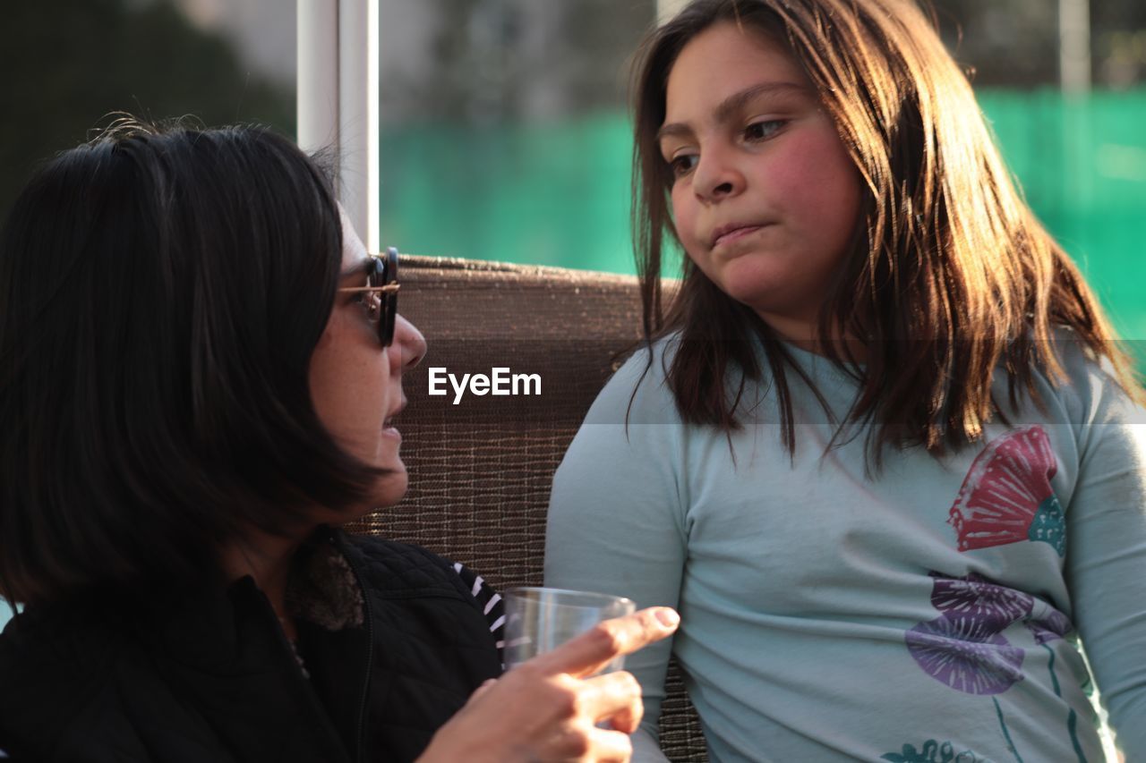 Mature woman with drink looking towards daughter