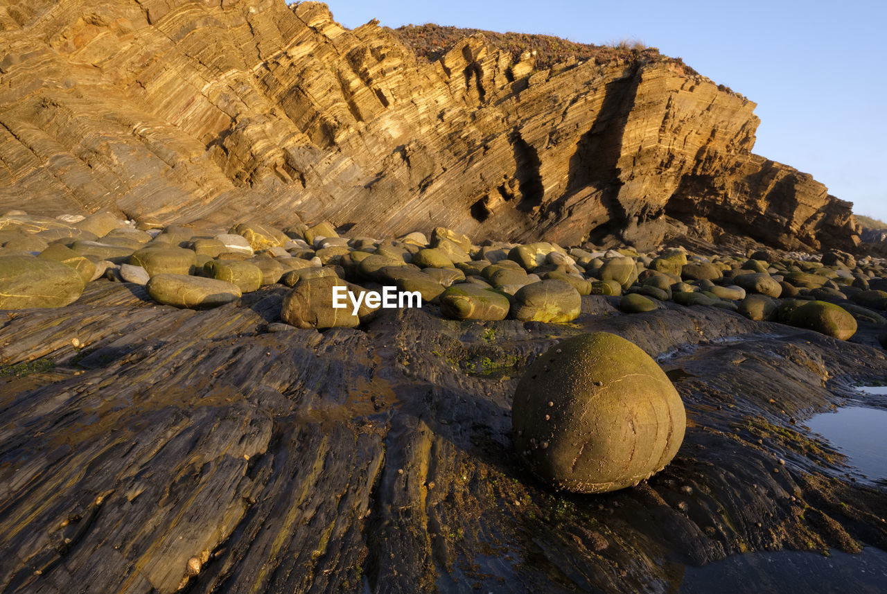 rock, nature, landscape, land, environment, sky, rock formation, geology, scenics - nature, beauty in nature, no people, travel destinations, wilderness, non-urban scene, natural environment, mountain, travel, water, cliff, terrain, outdoors, sea, tranquility, clear sky, formation, day, coast, physical geography, animal wildlife, wadi, volcano