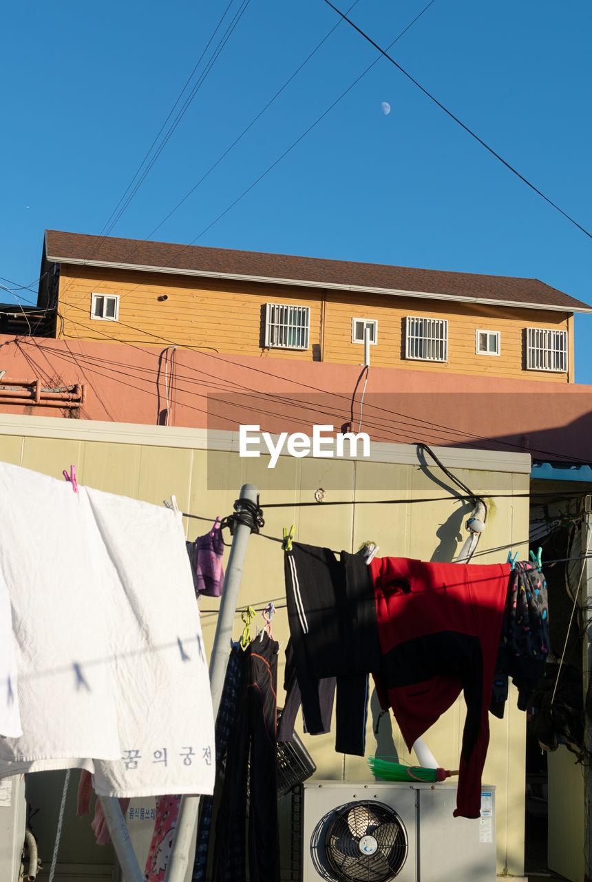 laundry, architecture, clothesline, building exterior, drying, hanging, built structure, sky, cable, no people, building, clothing, nature, day, clear sky, city, electricity, residential district, vehicle, blue, outdoors