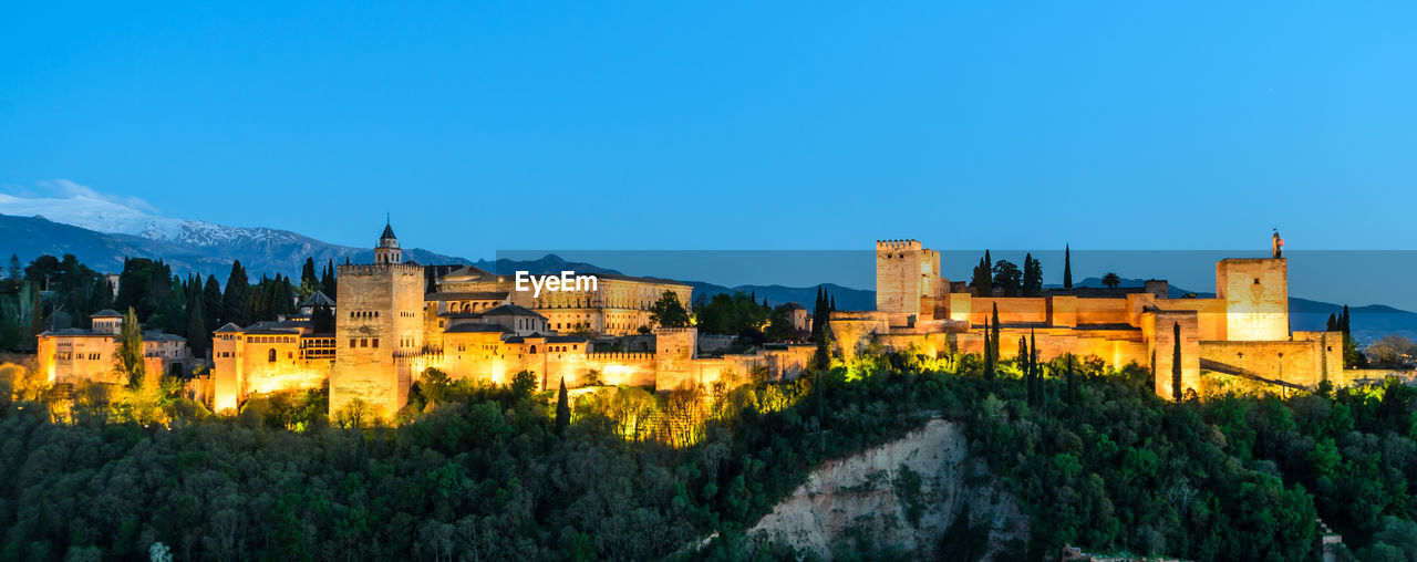 Panoramic view of buildings in city against clear blue sky