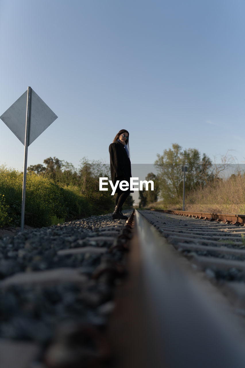 Man standing on railroad track against clear sky