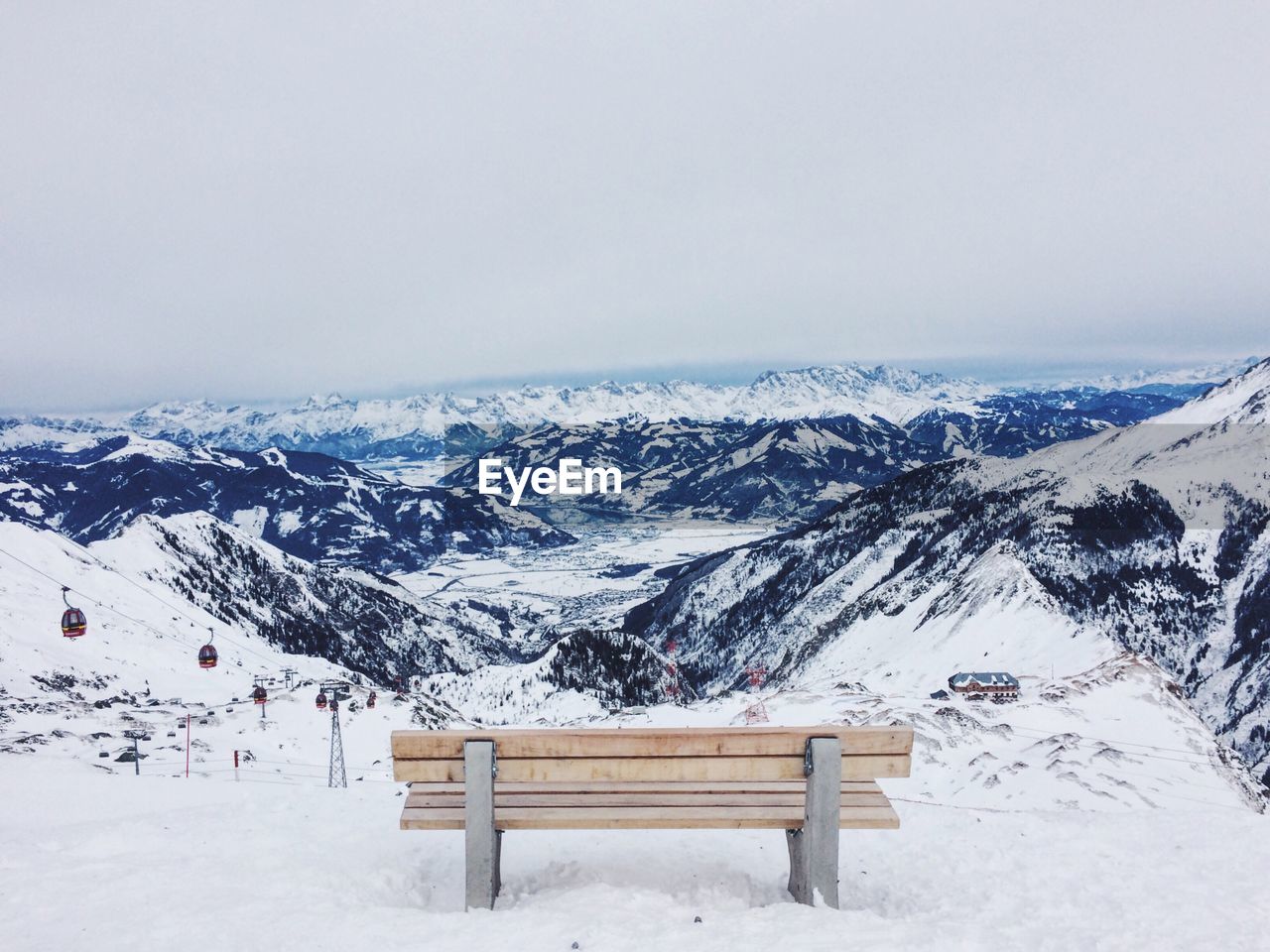 Empty bench on snowcapped mountain against sky