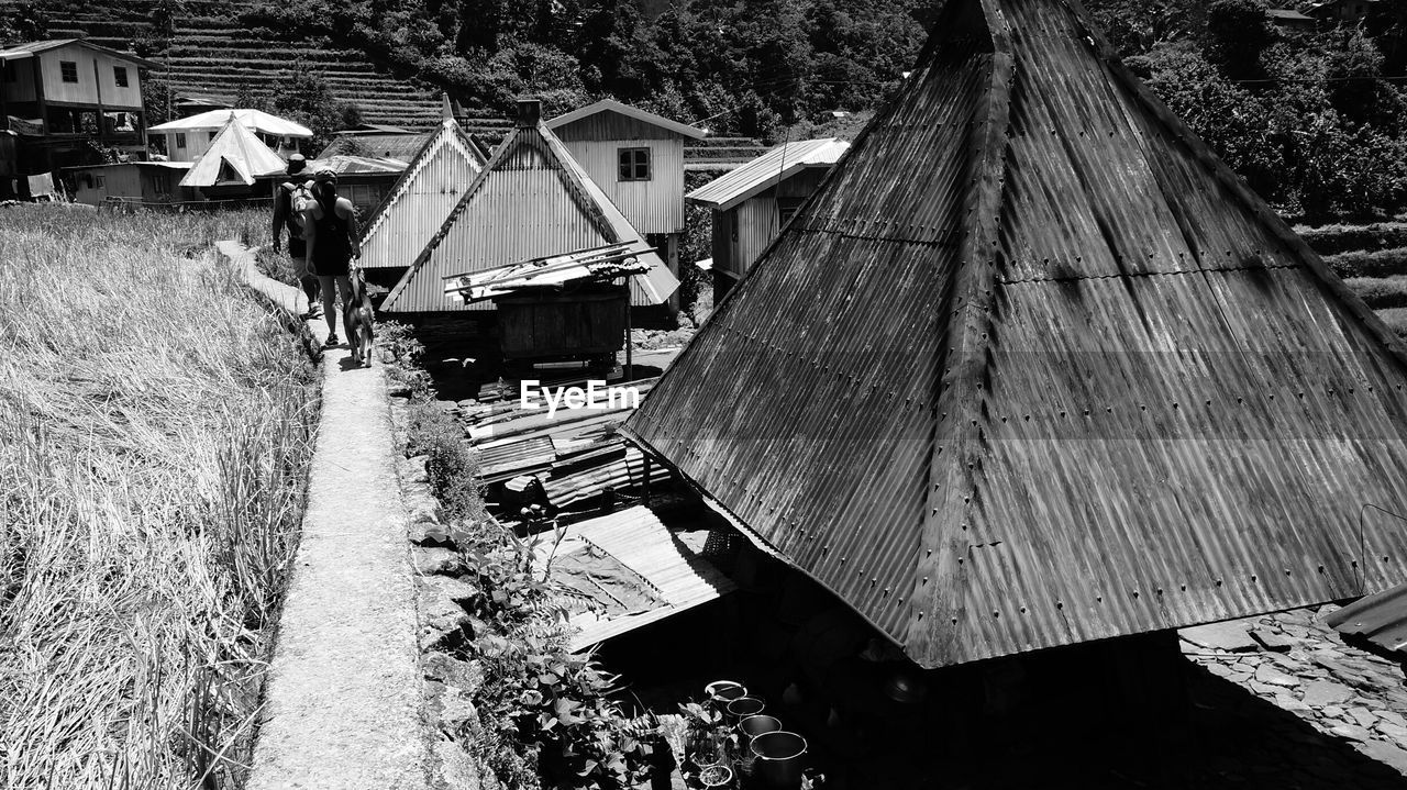 Rear view of people walking by houses