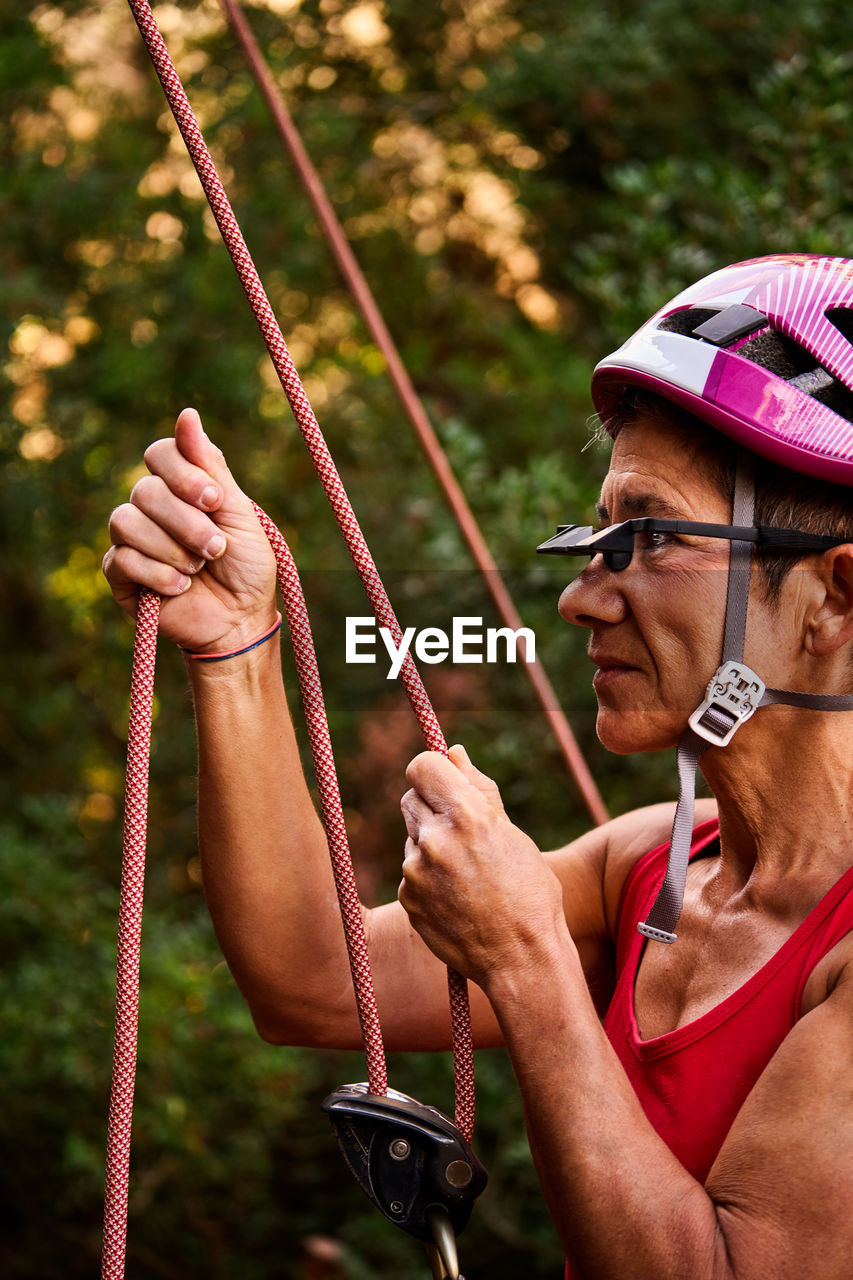 Active senior woman wearing prism glasses while holding climbing rope