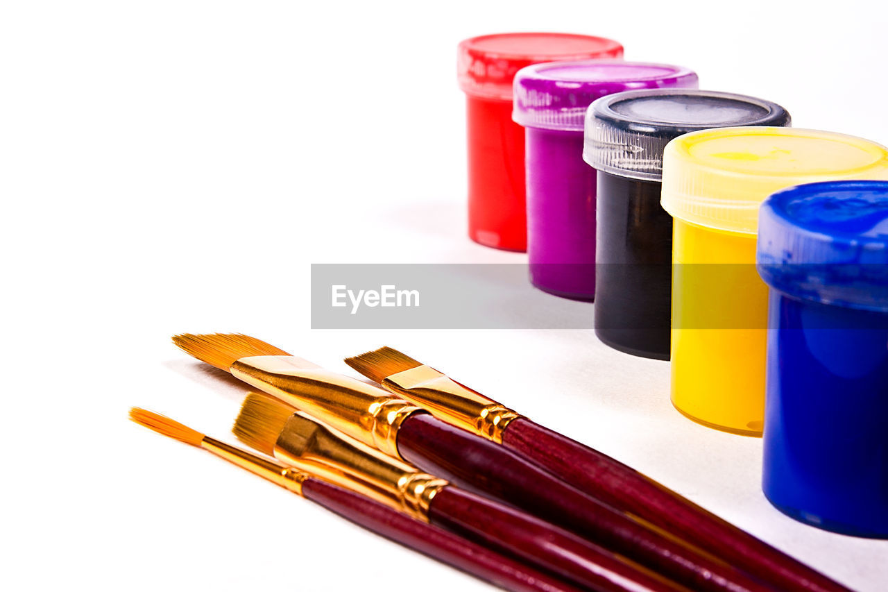 Close-up of paintbrushes and watercolor paints against white background