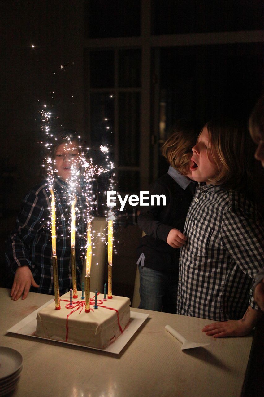 Sparklers burning on birthday cake by children at home