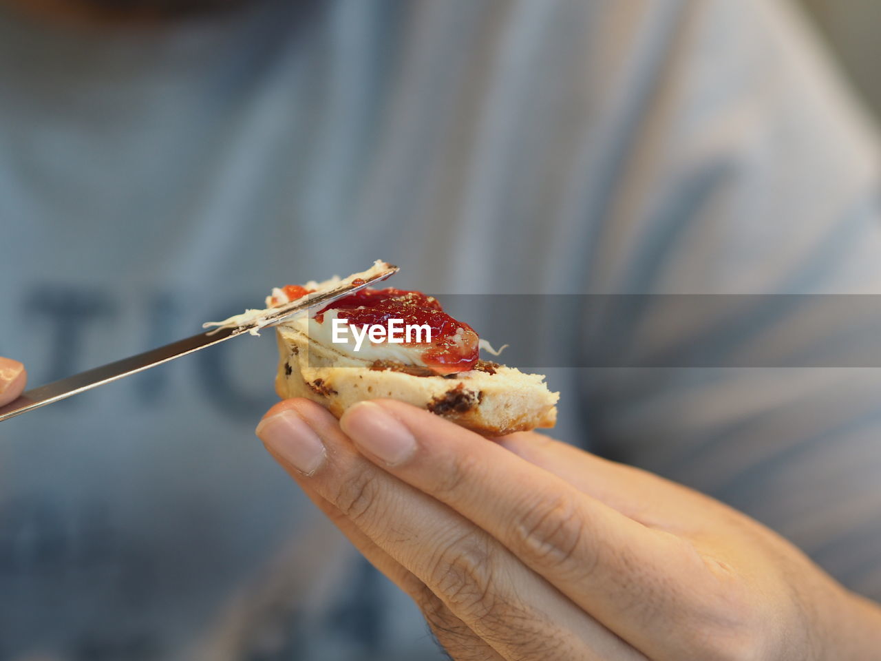 Close-up of person spreading jam on scone