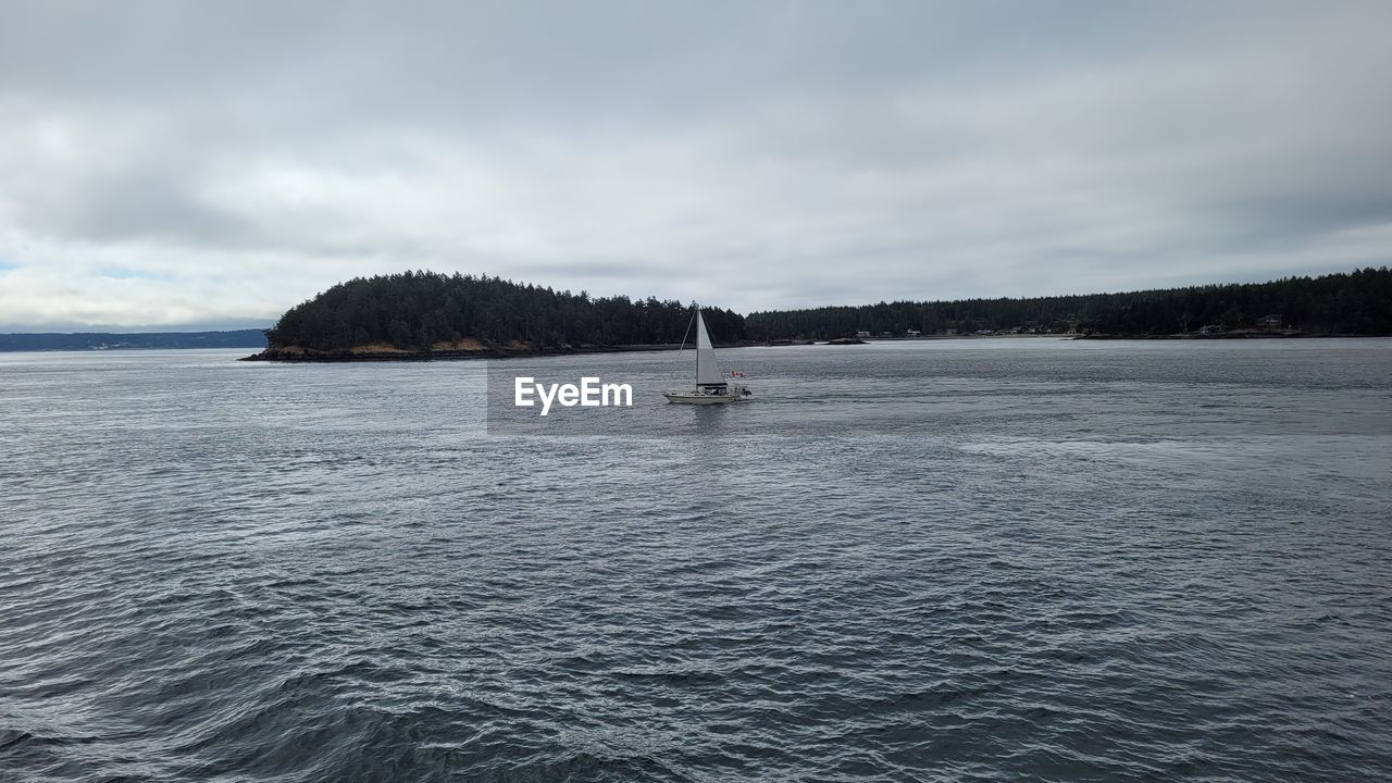 water, sky, sea, cloud, vehicle, scenics - nature, beauty in nature, nature, boat, shore, tranquil scene, nautical vessel, tranquility, boating, transportation, ocean, land, ship, day, coast, no people, horizon, non-urban scene, bay, travel, outdoors, environment, travel destinations, wave, holiday, idyllic, body of water, mode of transportation, island, mountain, vacation, overcast, trip, landscape, beach, sailboat