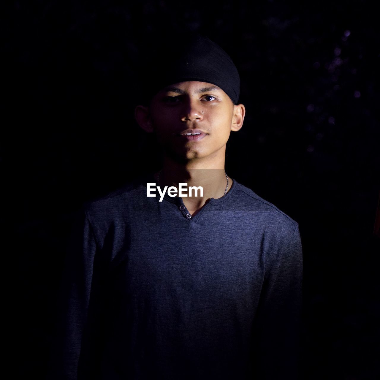 Portrait of teenage boy standing against black background