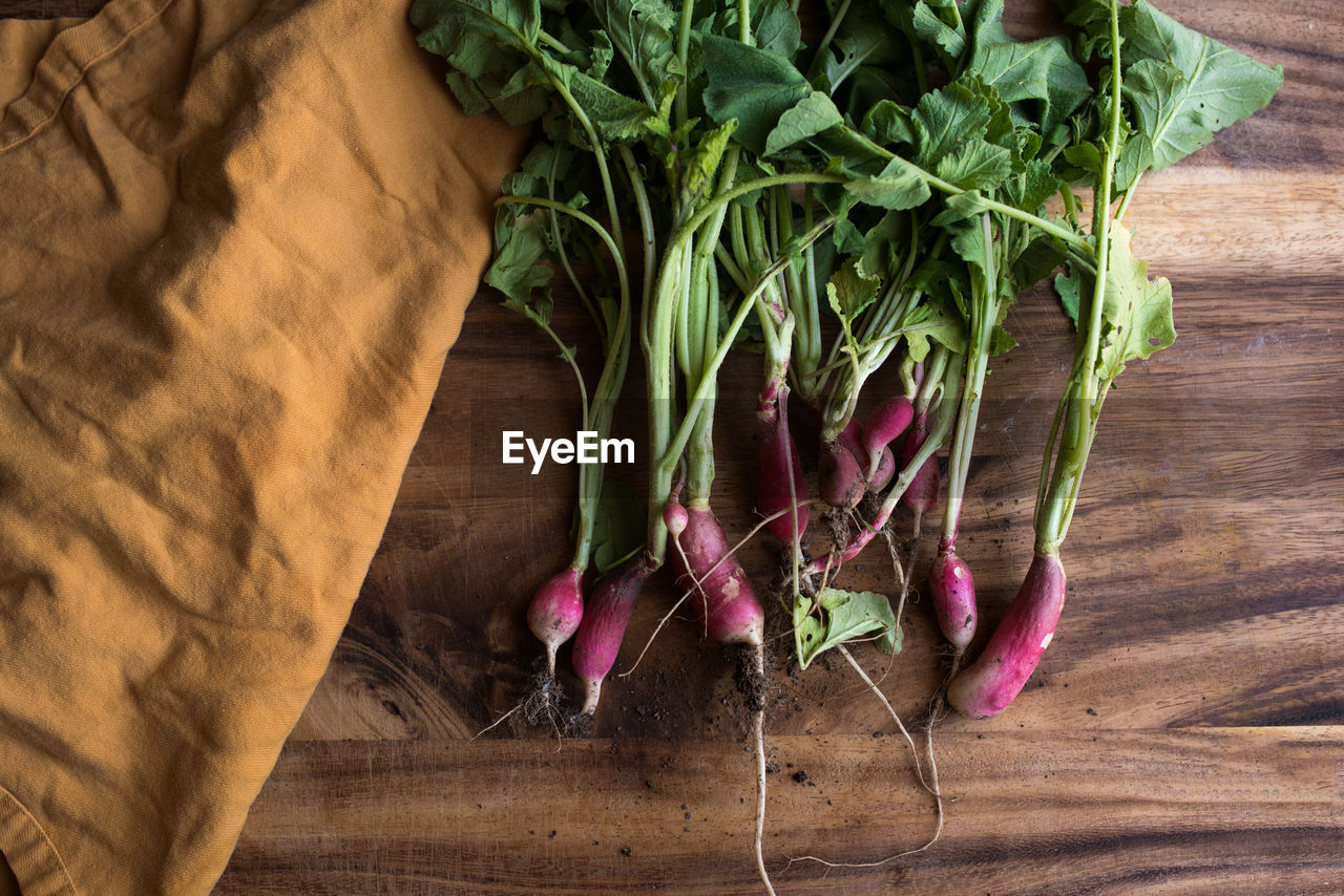 Bunch of radishes on cutting board with yellow napkin