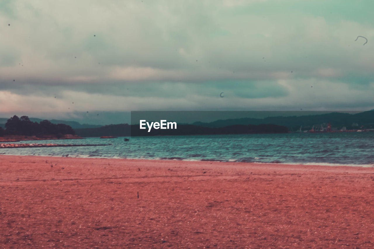 VIEW OF BEACH AGAINST CLOUDY SKY